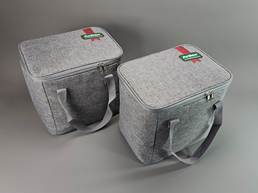 Zwei graue Kuehltaschen aus rPET-Polyester mit Adler-Schwarzwald-Logo im Transferdruck