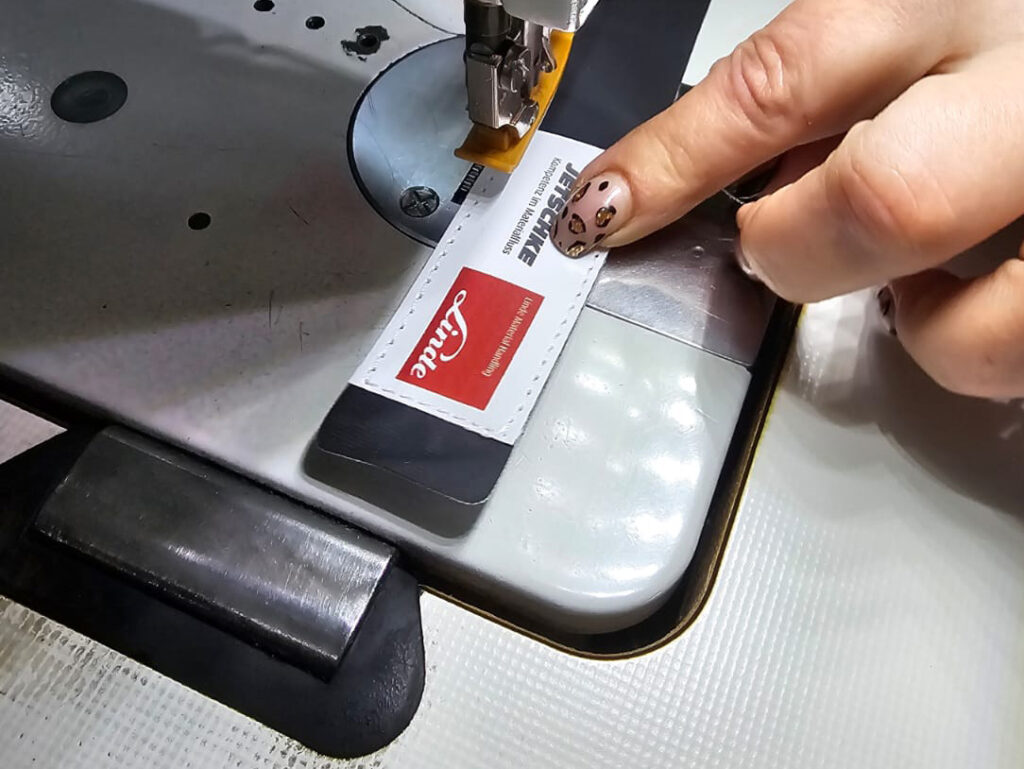 Das Label wird auf den Anhaenger genaeht