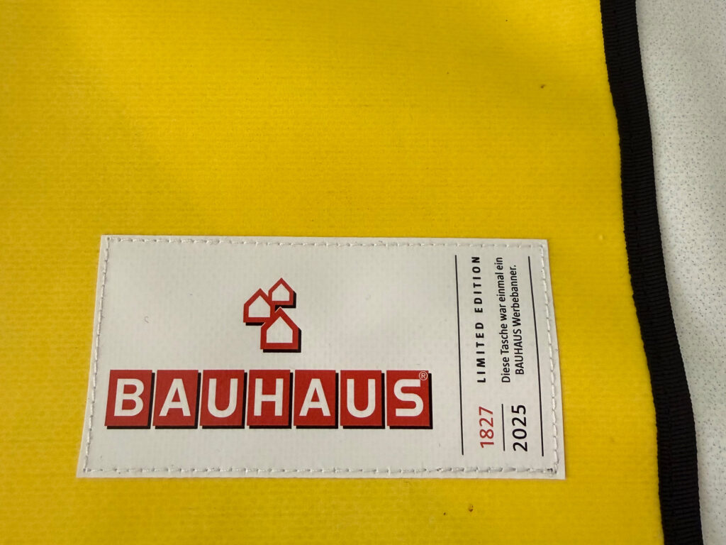Label with unique-piece counter: limited edition, number 1827 of 2025, on yellow banner fabric