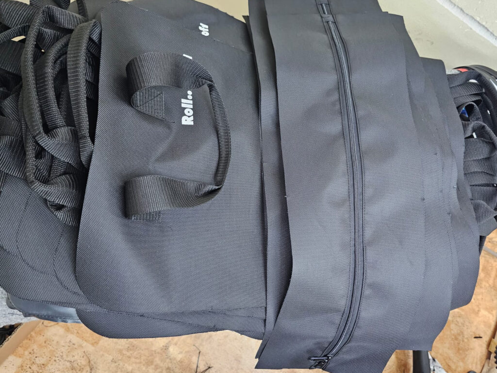 Zugeschnittene Polyester-Teile mit Gurtband-Henkeln und Reissverschluss vor der Montage