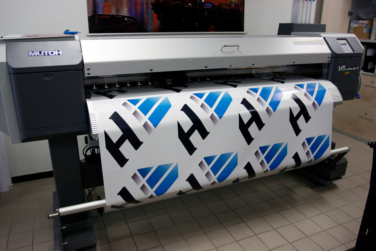 Die erste eigene Digitaldruckmaschine (2009): Grossformatdrucker beim vollflaechigen Bedrucken von Planenmaterial