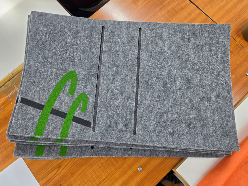 Bedruckte Filz-Zuschnitte im Stapel, Logo im Siebdruck vor der Konfektion