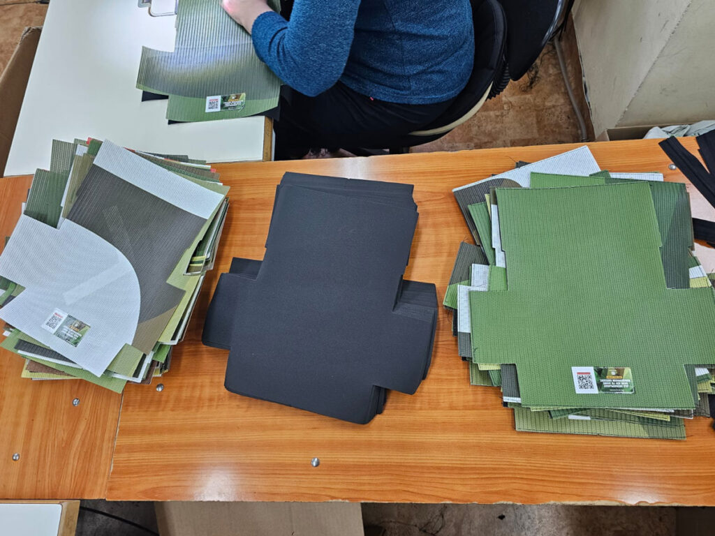 Sortierte Zuschnitte aus recyceltem Bannerstoff auf dem Werktisch der Näherei